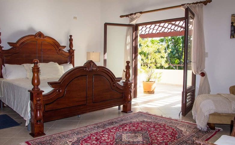 buyDRproperty Bedroom in Beautiful VILLA BRILLANTE with patio access and a large wooden bed. Sosua Real Estate