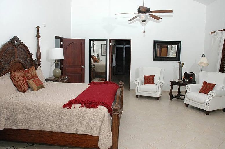 buyDRproperty Elegant bedroom in Beautiful VILLA BRILLANTE features a four-poster bed and seating area. Sosua Real Estate