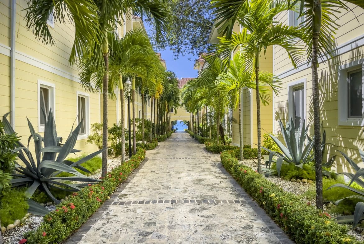 buyDRproperty Walkway lined with palm trees, gardens, and buildings leading to the ocean. Sosua condo complex. Sosua Real Estate