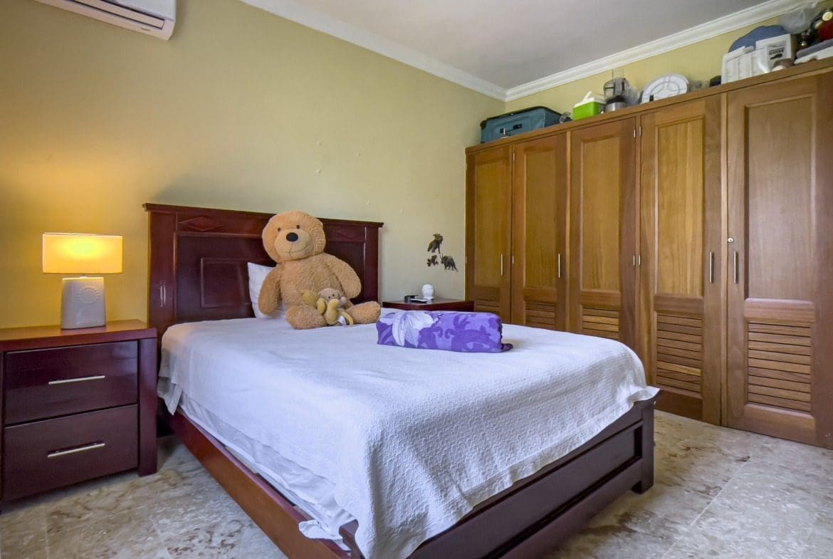 buyDRproperty Cozy bedroom with a large teddy bear on the bed Sosua Real Estate
