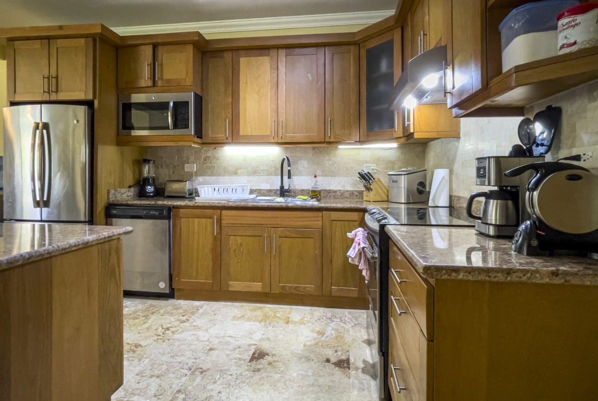buyDRproperty Kitchen with wooden cabinets, stainless steel appliances, and granite countertop. Sosua Real Estate
