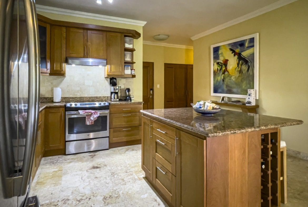 buyDRproperty Wooden kitchen with granite countertops, island with wine rack, and stainless steel appliances. Sosua Real Estate
