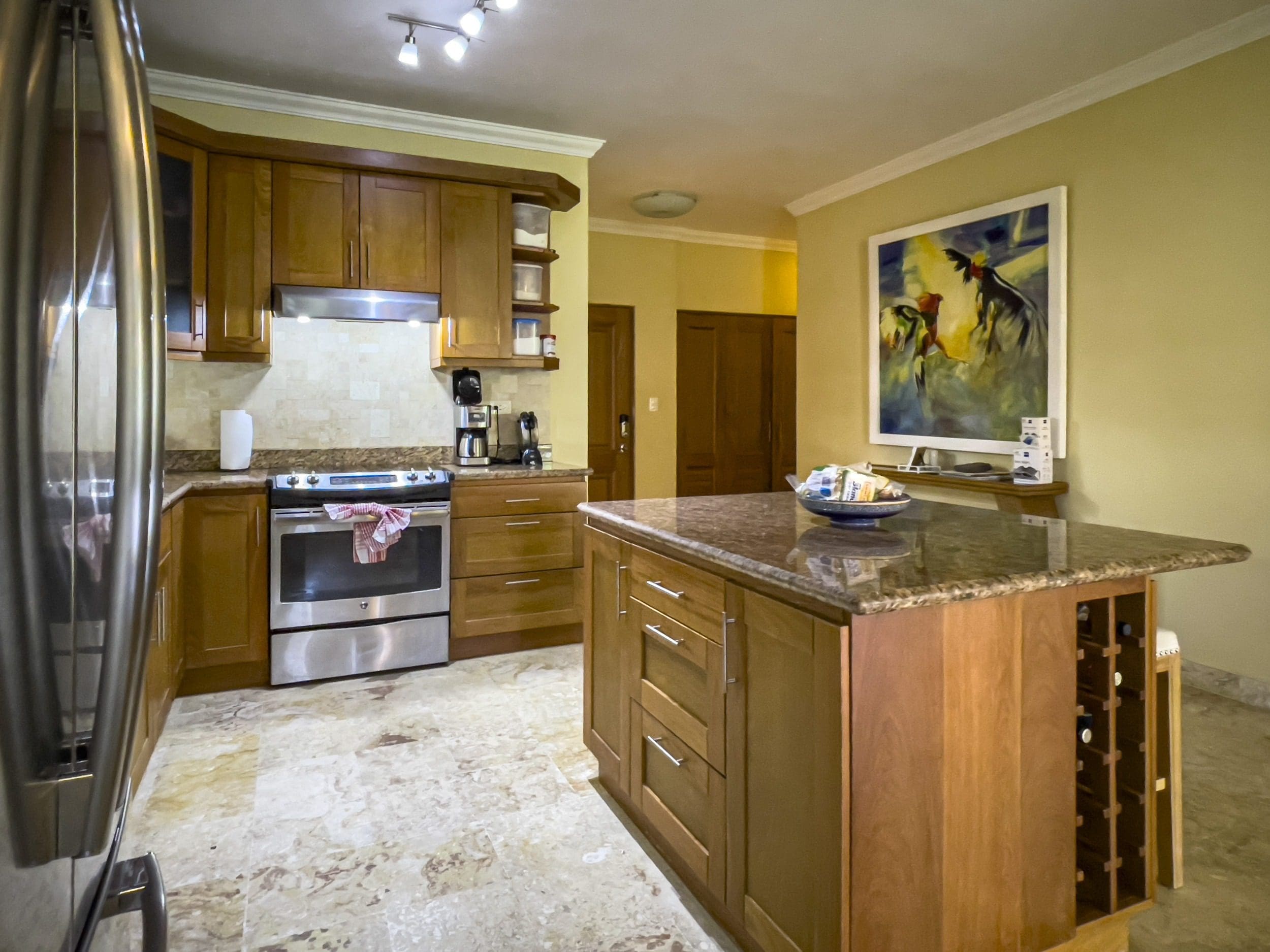 buyDRproperty Wooden kitchen with granite countertops, island with wine rack, and stainless steel appliances. Sosua Real Estate