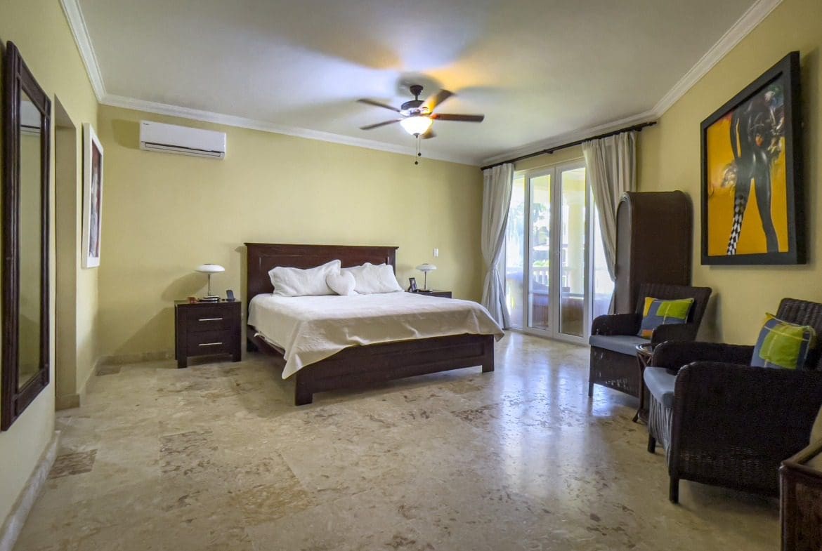 buyDRproperty Spacious bedroom in a Sosua oceanfront condo, featuring a large bed and seating area. Sosua Real Estate