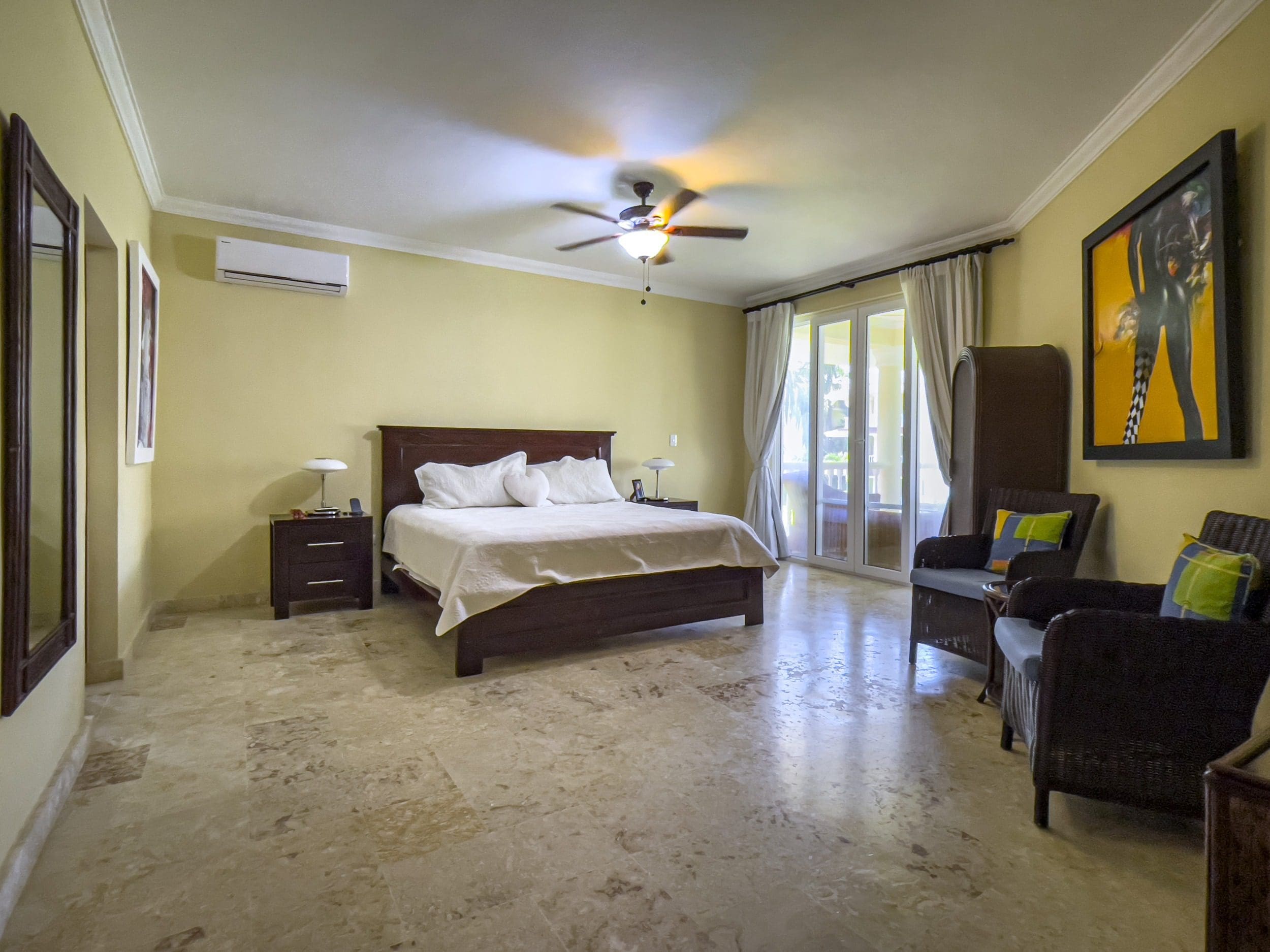 buyDRproperty Spacious bedroom in a Sosua oceanfront condo, featuring a large bed and seating area. Sosua Real Estate