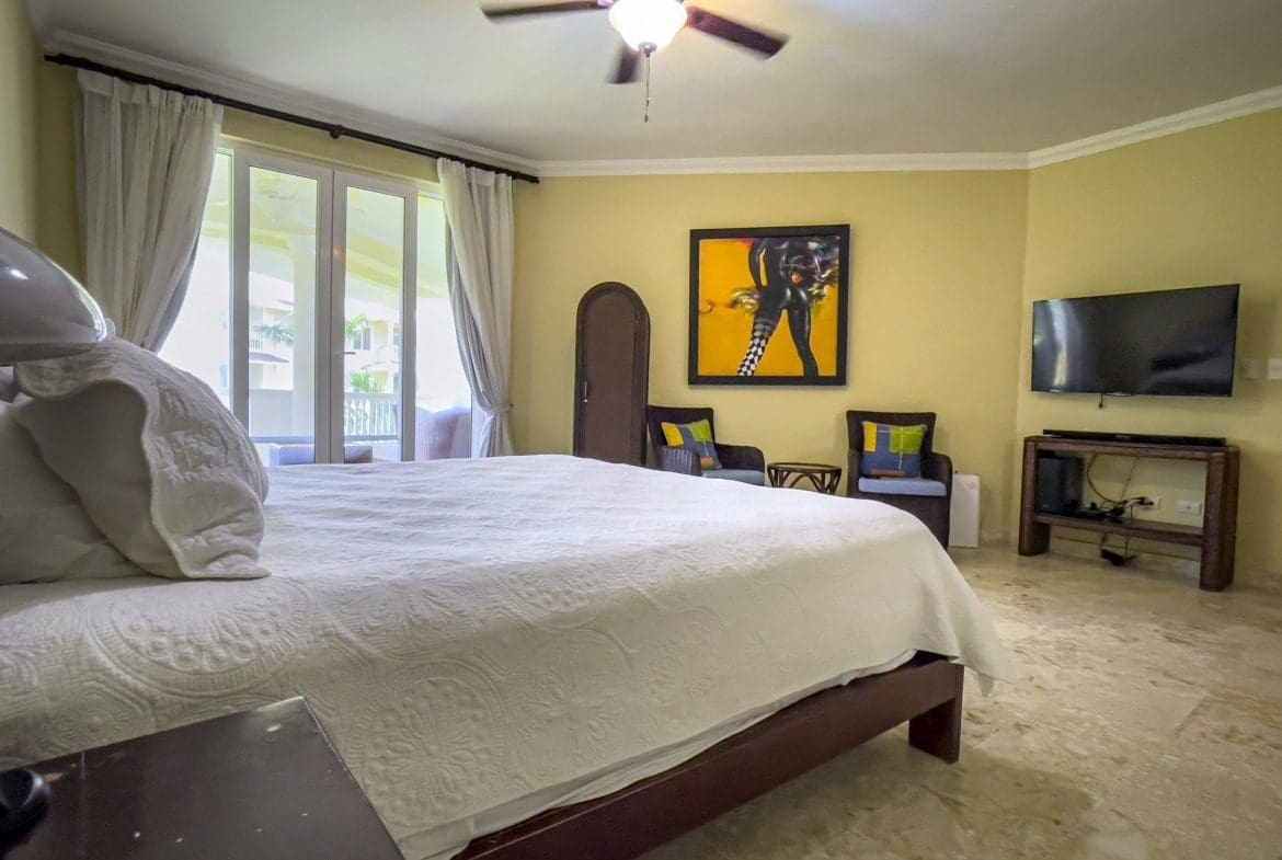 buyDRproperty Bedroom in Sosua condo with ocean view, featuring a bed, artwork, and TV. Sosua Real Estate