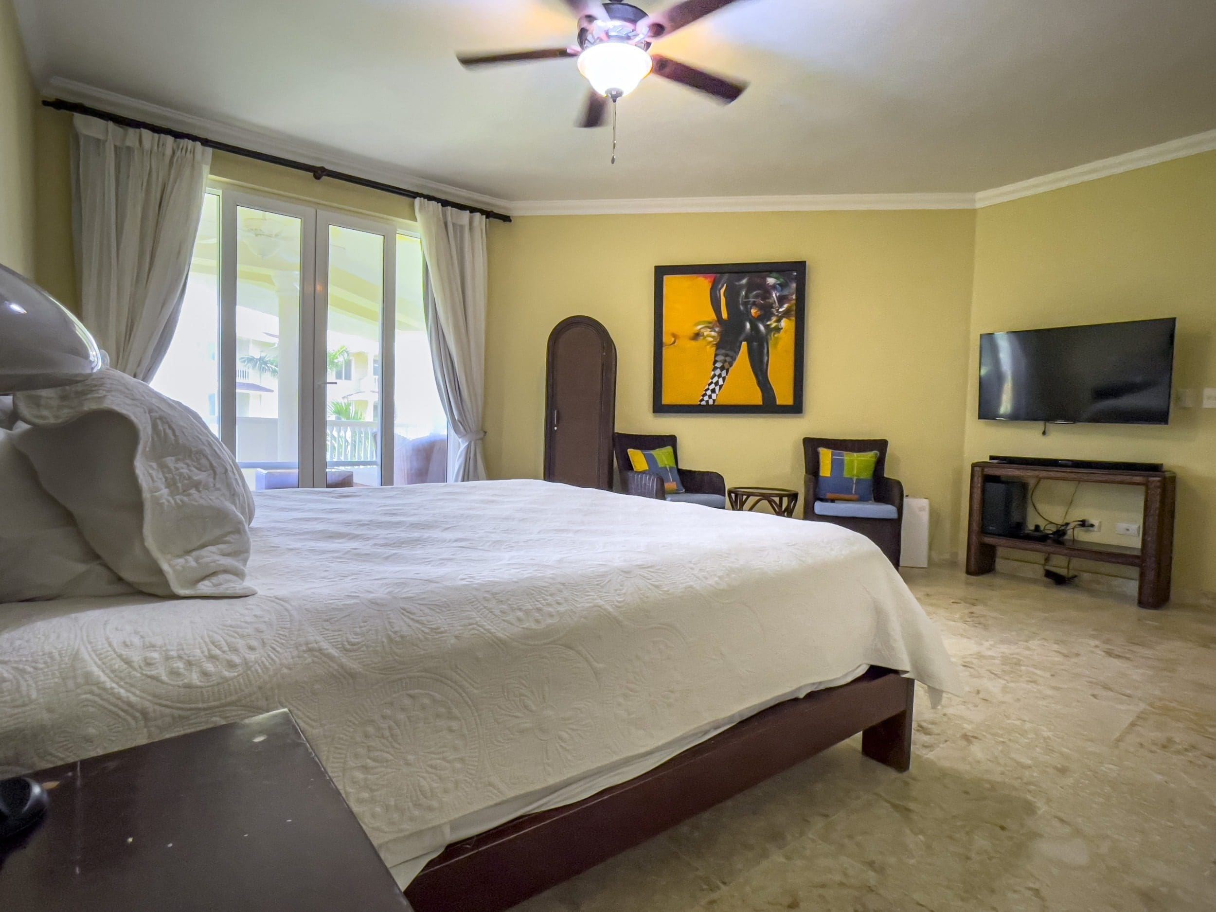 buyDRproperty Bedroom in Sosua condo with ocean view, featuring a bed, artwork, and TV. Sosua Real Estate