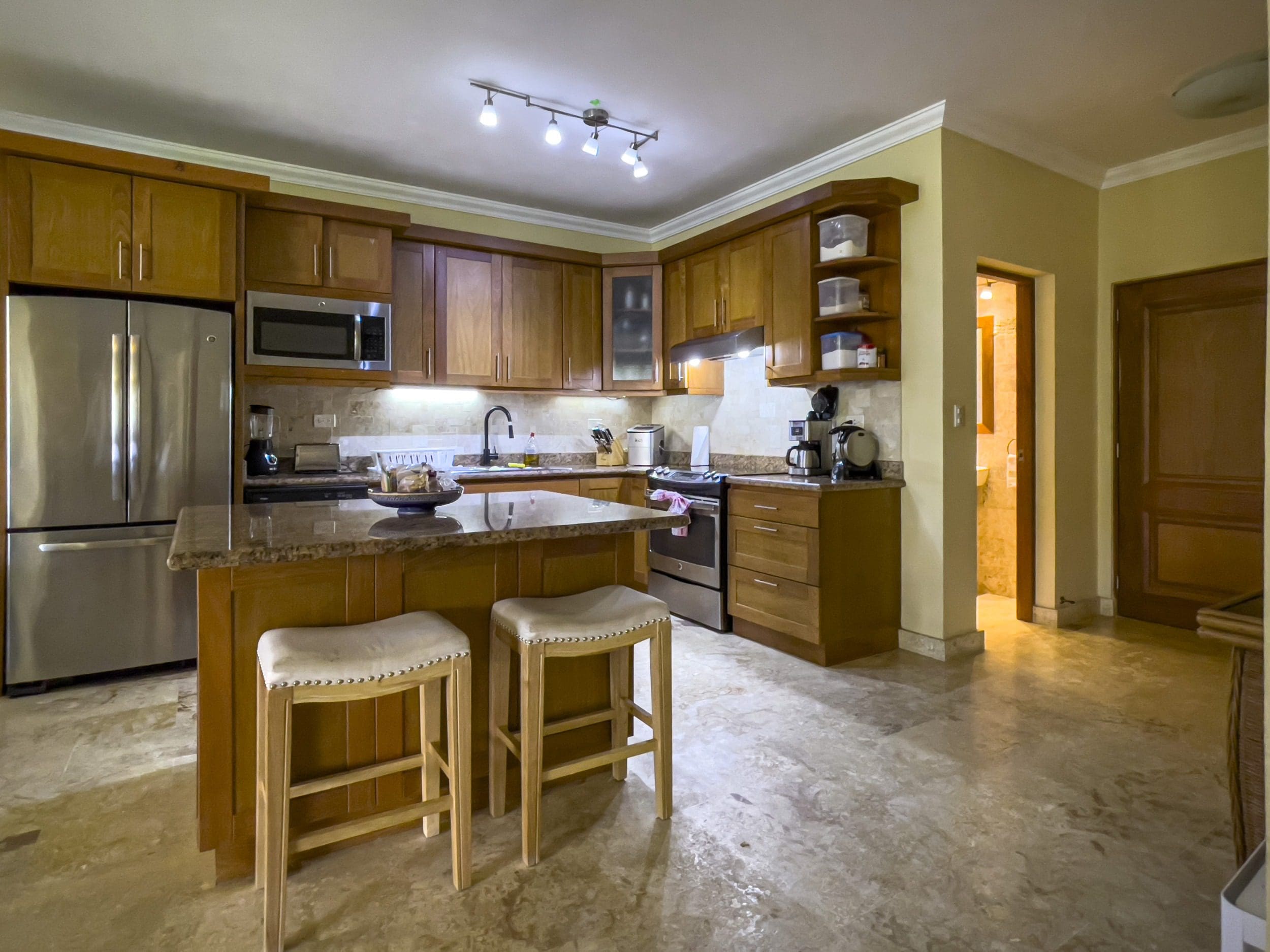 buyDRproperty Spacious kitchen with wooden cabinets and granite countertops in a Sosua condo. Sosua Real Estate