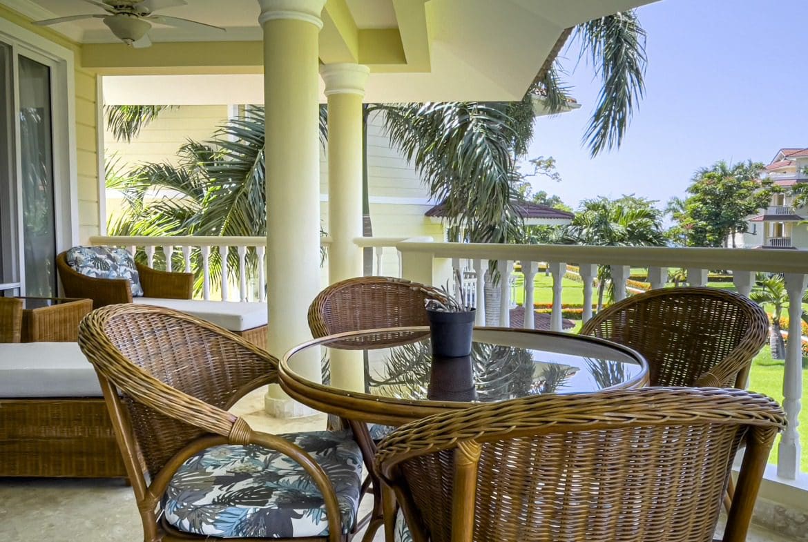 buyDRproperty Wicker patio furniture on a balcony overlooking a tropical view from an oceanfront condo in Sosua. Sosua Real Estate