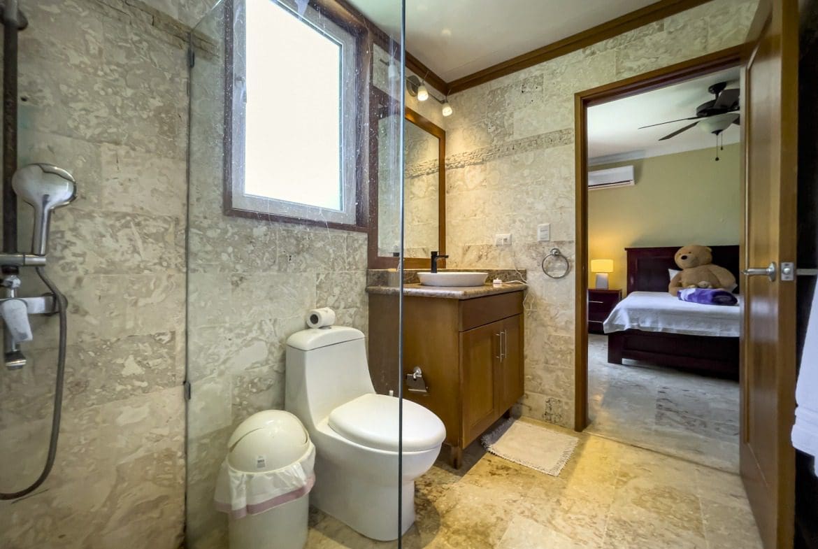 buyDRproperty Bathroom with shower, toilet, and vanity in a Sosua condo. Sosua Real Estate