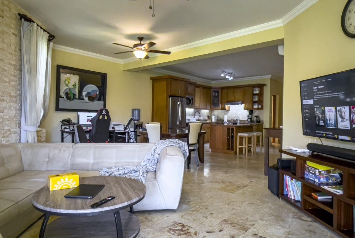 buyDRproperty Living room with a view into the kitchen; TV showing "Slow Horses" series. Sosua Real Estate