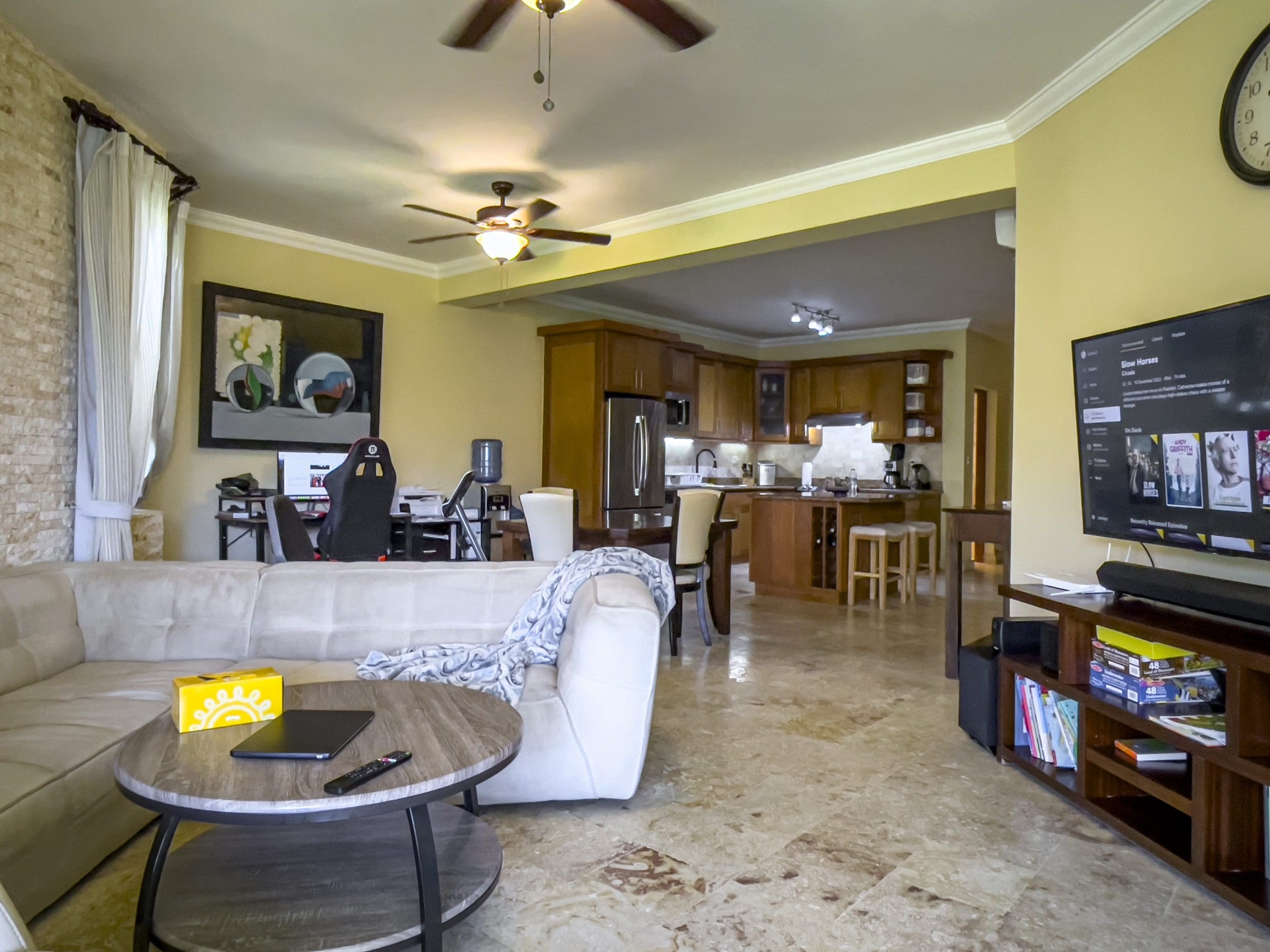 buyDRproperty Living room with a view into the kitchen; TV showing "Slow Horses" series. Sosua Real Estate