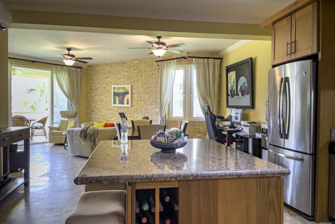 buyDRproperty Open-concept kitchen with island, wine rack, and stainless steel refrigerator in a Sosua condo. Sosua Real Estate