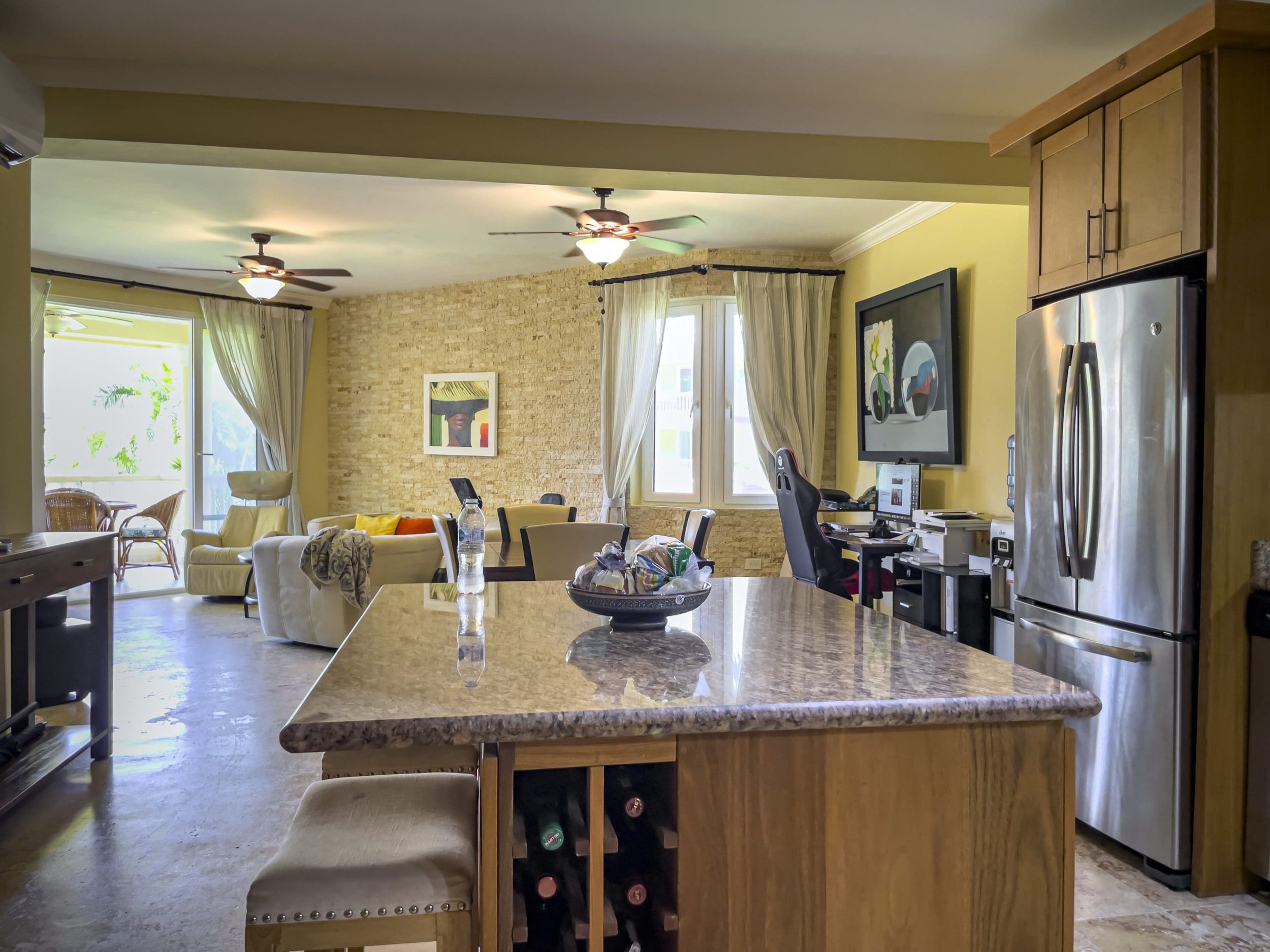 buyDRproperty Open-concept kitchen with island, wine rack, and stainless steel refrigerator in a Sosua condo. Sosua Real Estate