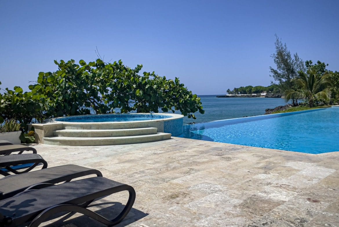 buyDRproperty Luxury oceanfront pool and jacuzzi overlooking the ocean on a sunny day. Sosua Real Estate