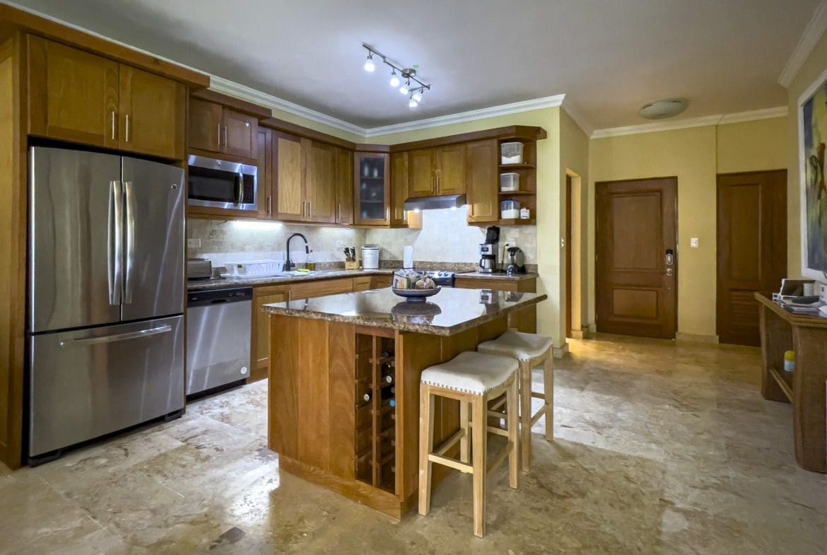 buyDRproperty Elegant Sosua condo kitchen with wooden cabinets, stainless steel appliances, and a kitchen island. Sosua Real Estate