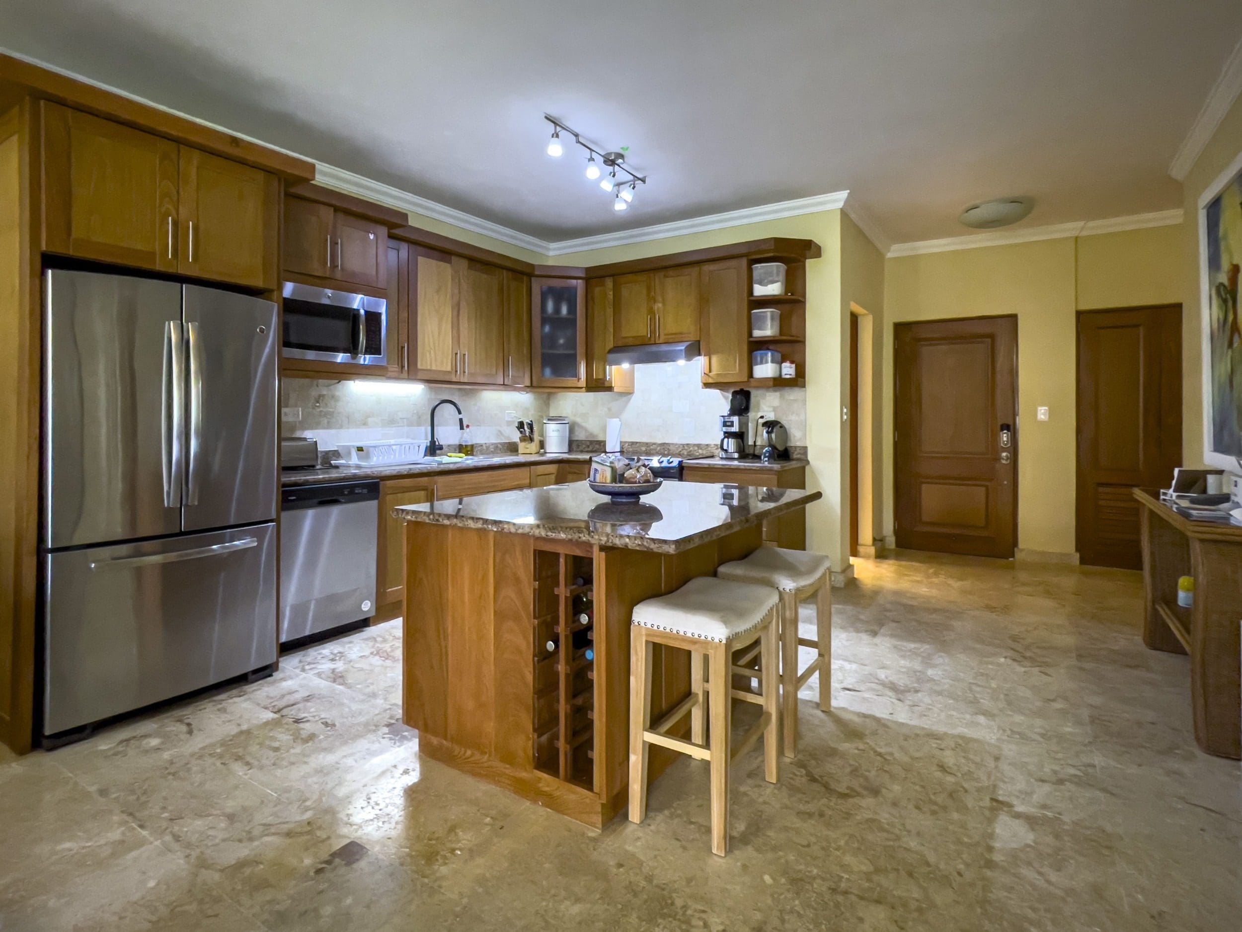 buyDRproperty Elegant Sosua condo kitchen with wooden cabinets, stainless steel appliances, and a kitchen island. Sosua Real Estate