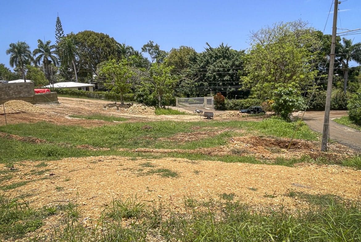 buyDRproperty Cleared building lot in Sosua with construction materials and a house in the background. Sosua Real Estate