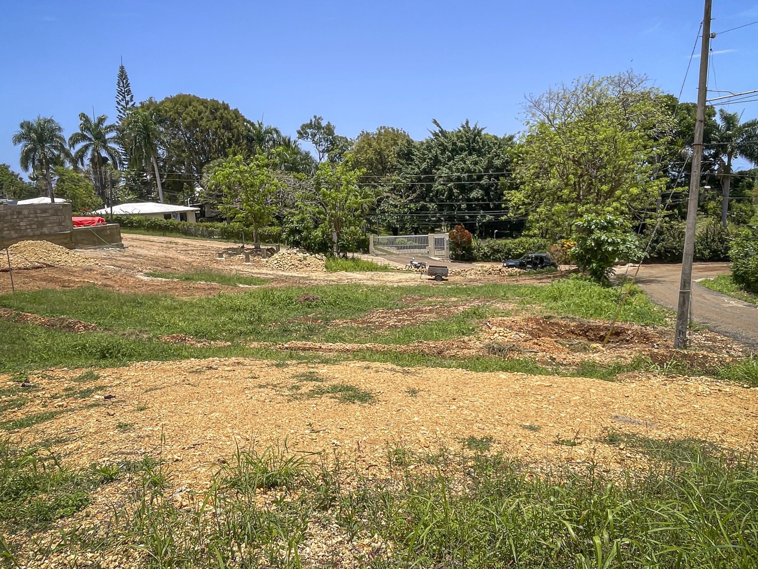 buyDRproperty Cleared building lot in Sosua with construction materials and a house in the background. Sosua Real Estate