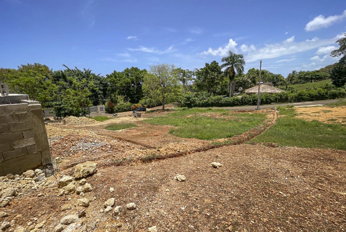 buyDRproperty Construction site in Sosua, Dominican Republic, with partially built wall and open land. Sosua Real Estate
