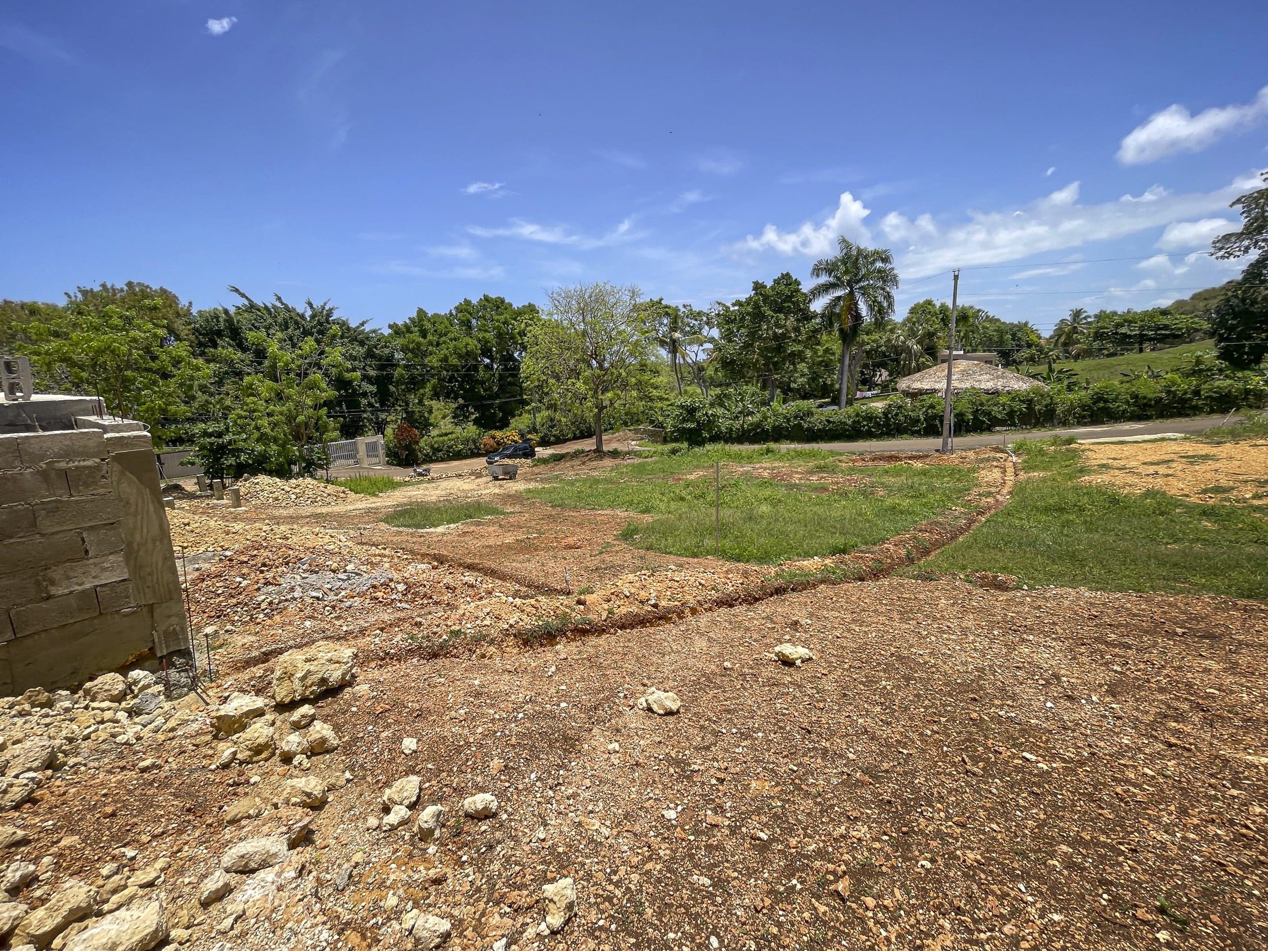 buyDRproperty Construction site in Sosua, Dominican Republic, with partially built wall and open land. Sosua Real Estate