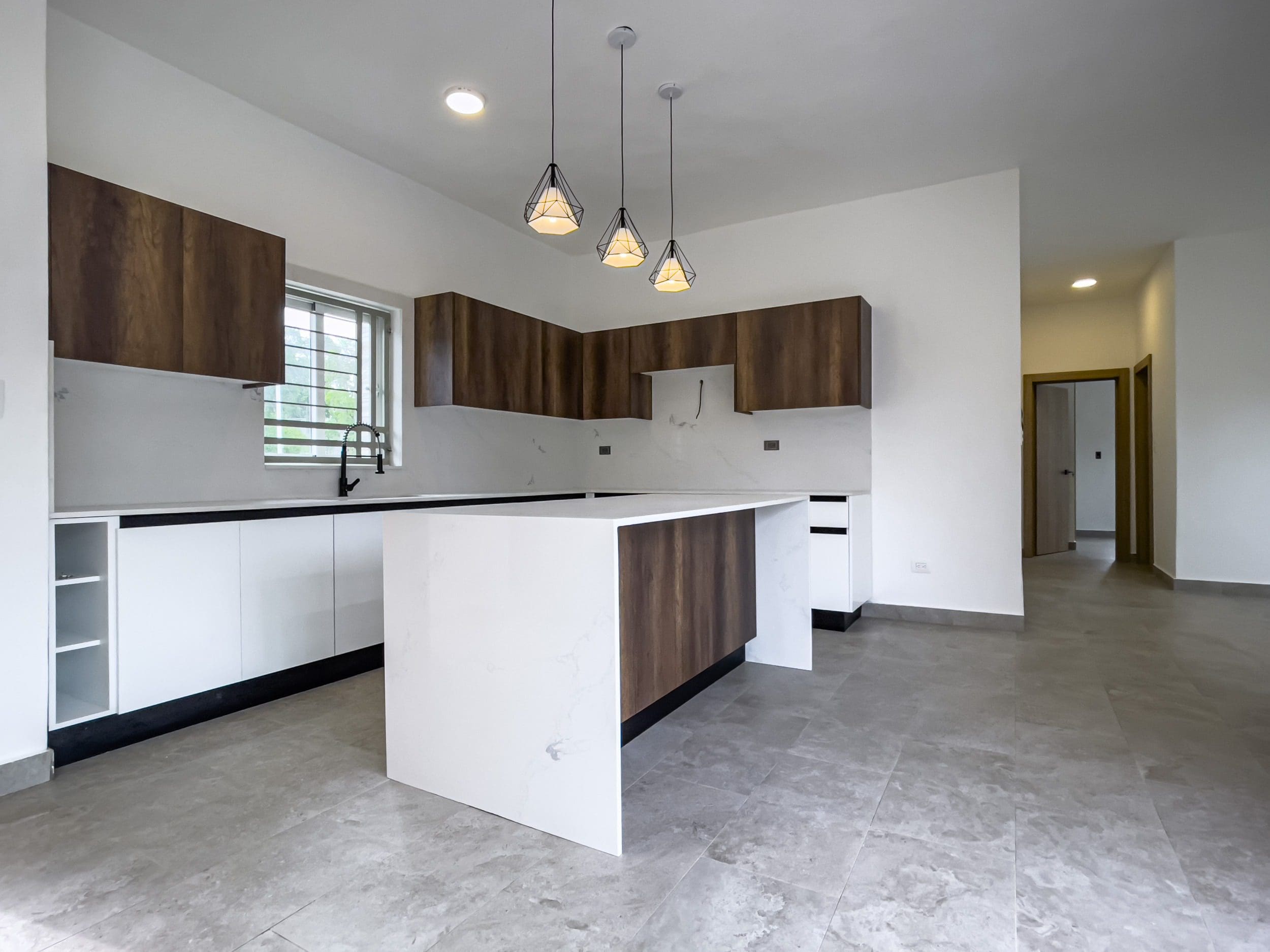 buyDRproperty Modern kitchen in a villa for sale with white cabinets and wood accents. Sosua Real Estate