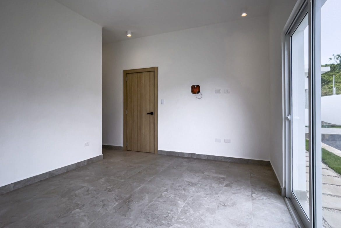 buyDRproperty Empty interior of a modern villa for sale with a door and large windows. Sosua Real Estate