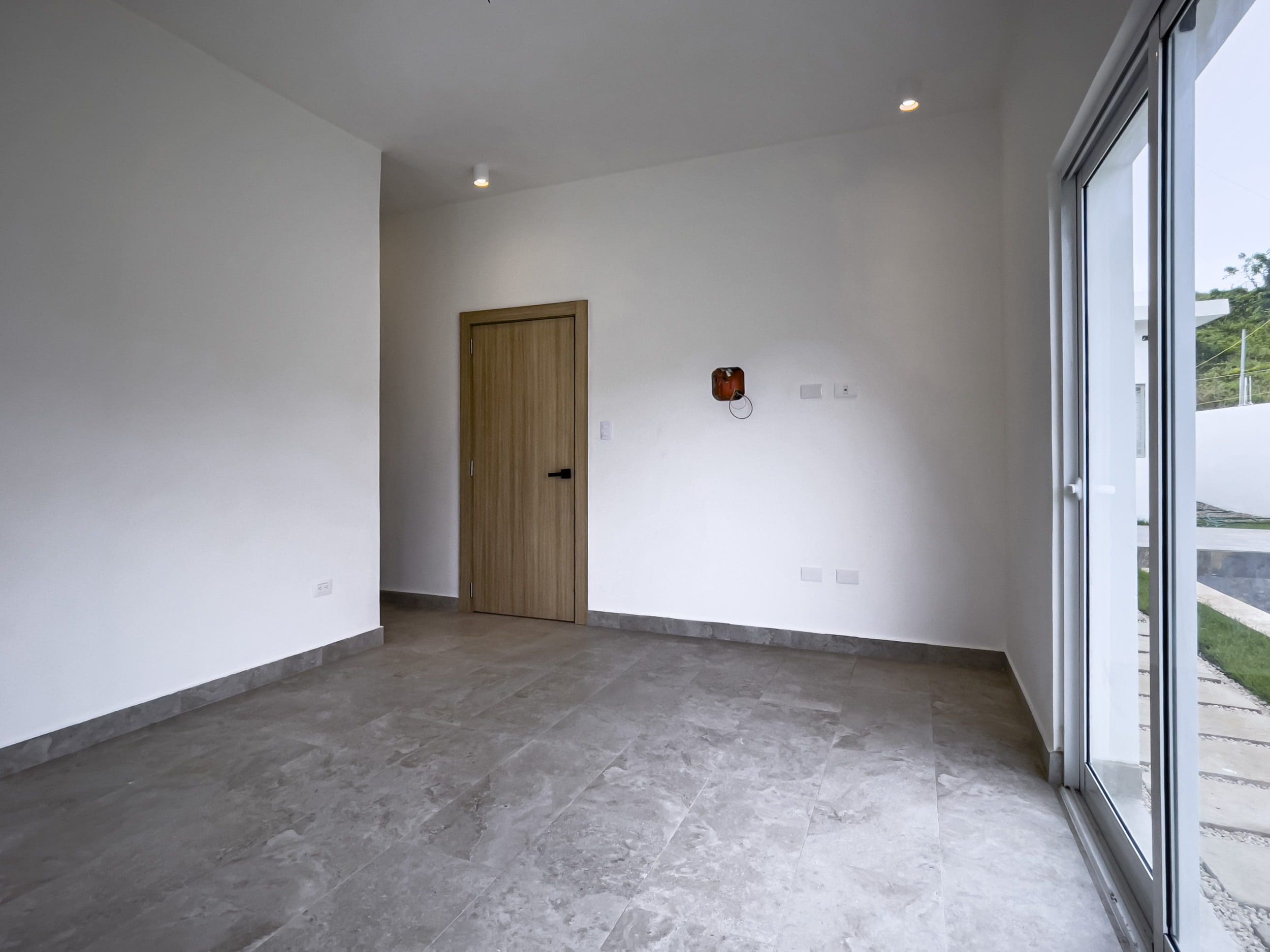 buyDRproperty Empty interior of a modern villa for sale with a door and large windows. Sosua Real Estate