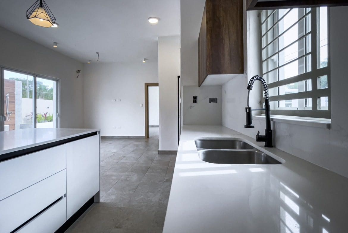 buyDRproperty Modern kitchen with white countertops, black faucet, and villa for sale. Sosua Real Estate