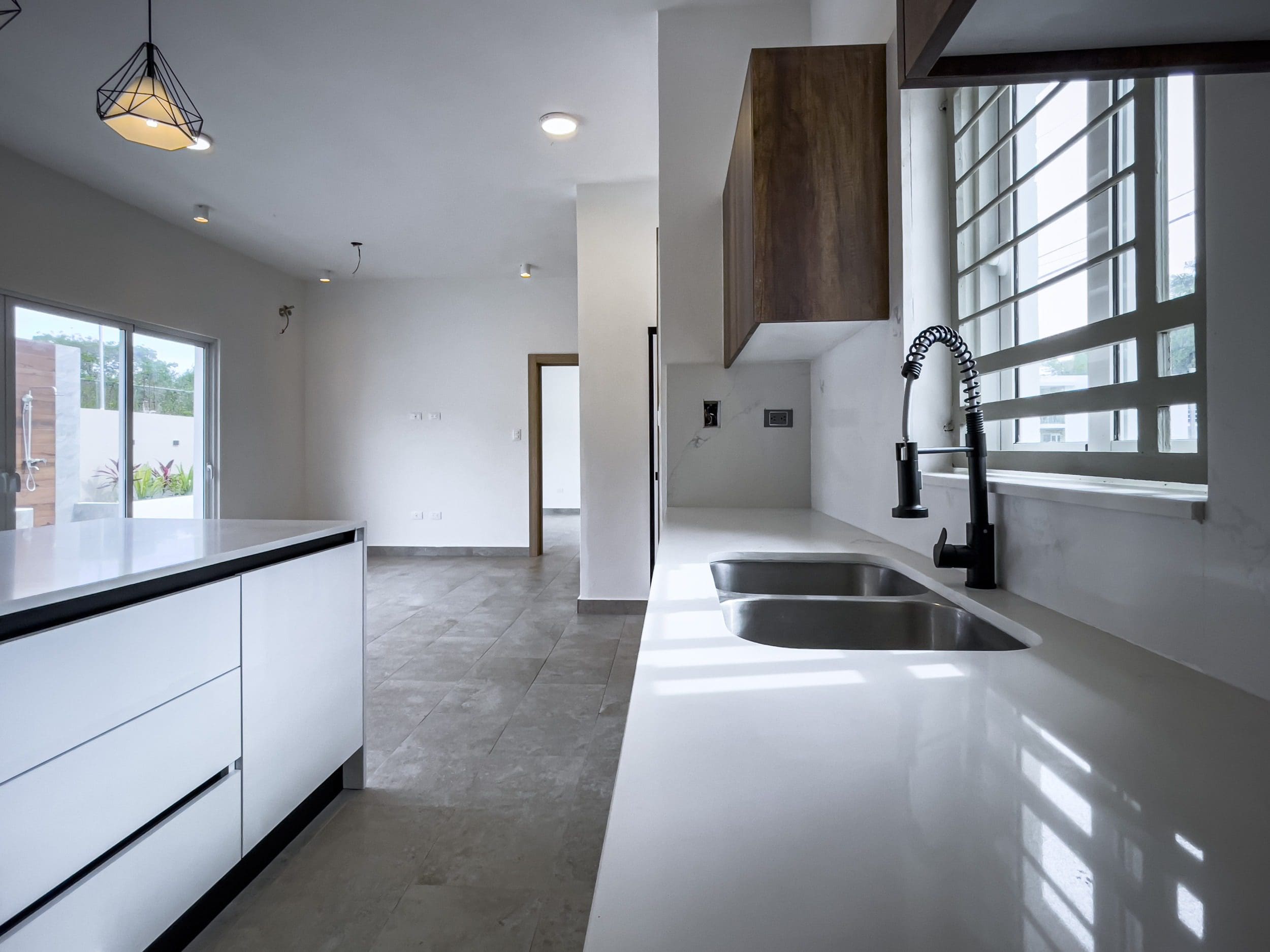 buyDRproperty Modern kitchen with white countertops, black faucet, and villa for sale. Sosua Real Estate