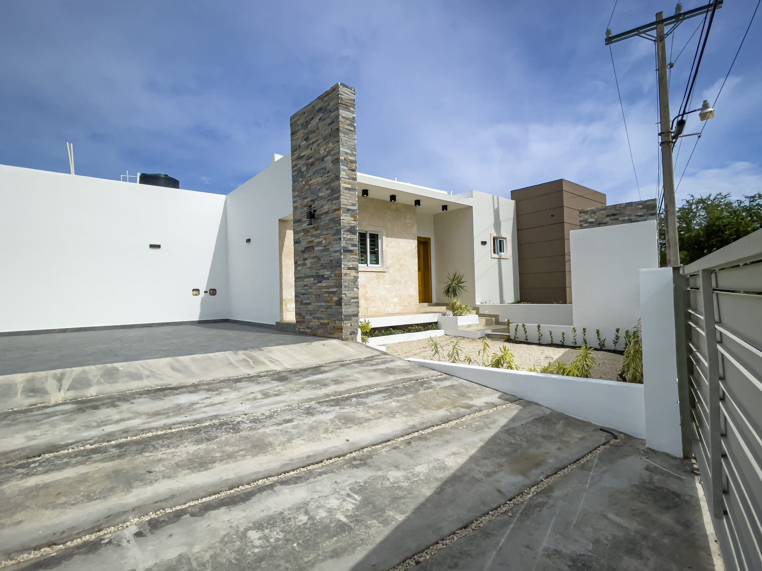 buyDRproperty Modern villa for sale in Sosua Hills with stone accents and concrete driveway Sosua Real Estate