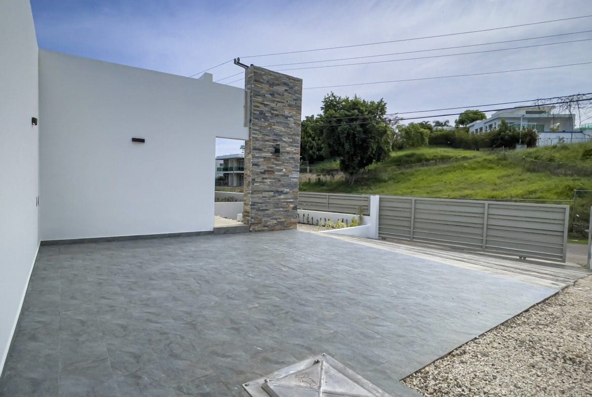 buyDRproperty Modern villa for sale with a stone accent wall and gray tiled patio. Sosua Real Estate