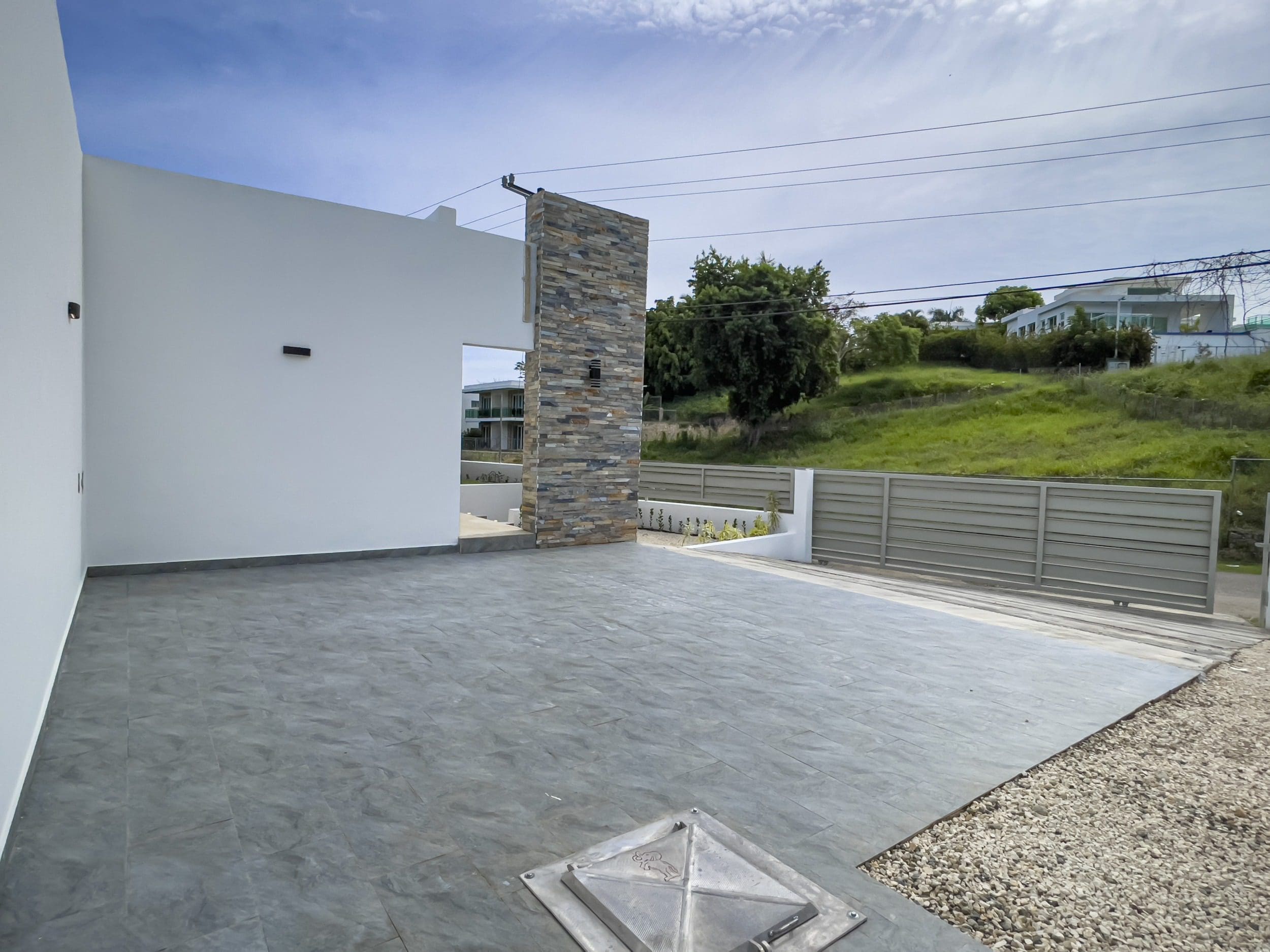 buyDRproperty Modern villa for sale with a stone accent wall and gray tiled patio. Sosua Real Estate