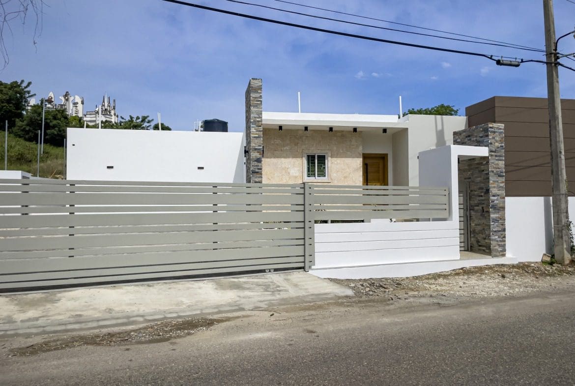 buyDRproperty Modern villa for sale in Sosua Hills with a gray gate and stone facade. Sosua Real Estate