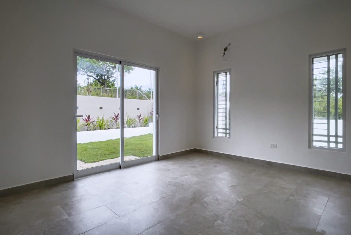 buyDRproperty Empty modern villa interior with large sliding glass doors and a view of the garden. Villa for sale. Sosua Real Estate