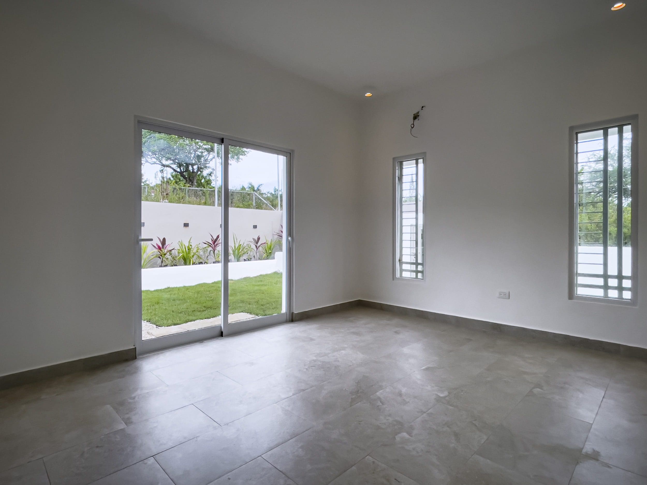 buyDRproperty Empty modern villa interior with large sliding glass doors and a view of the garden. Villa for sale. Sosua Real Estate