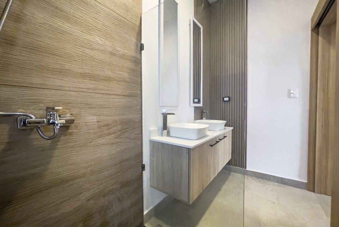 buyDRproperty Modern bathroom in a villa for sale featuring wood-paneled shower and dual sinks. Sosua Real Estate