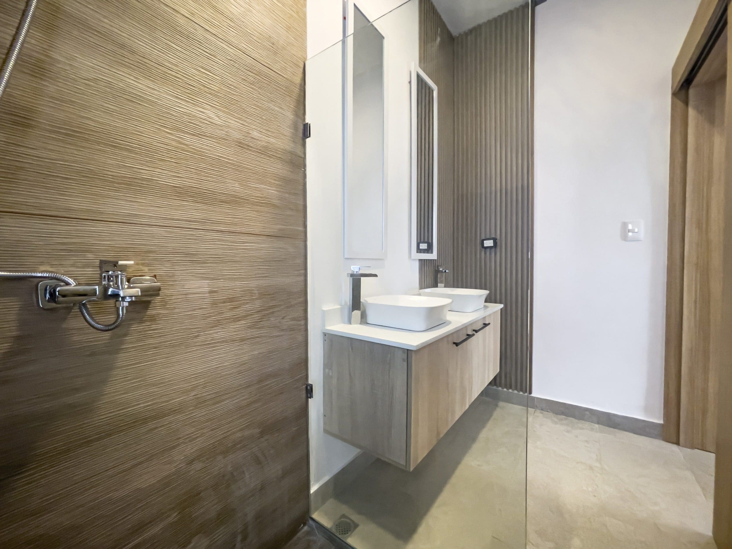 buyDRproperty Modern bathroom in a villa for sale featuring wood-paneled shower and dual sinks. Sosua Real Estate
