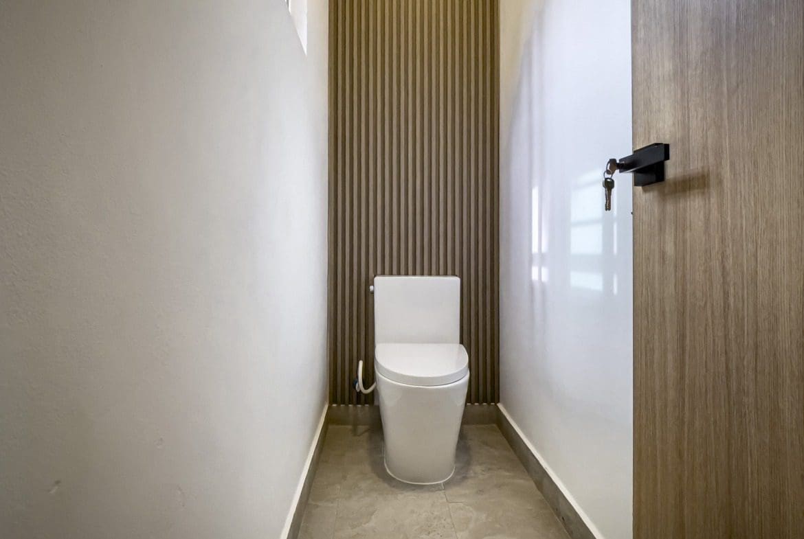 buyDRproperty Modern bathroom with white toilet and wooden accent wall. Villa For Sale. Sosua Real Estate