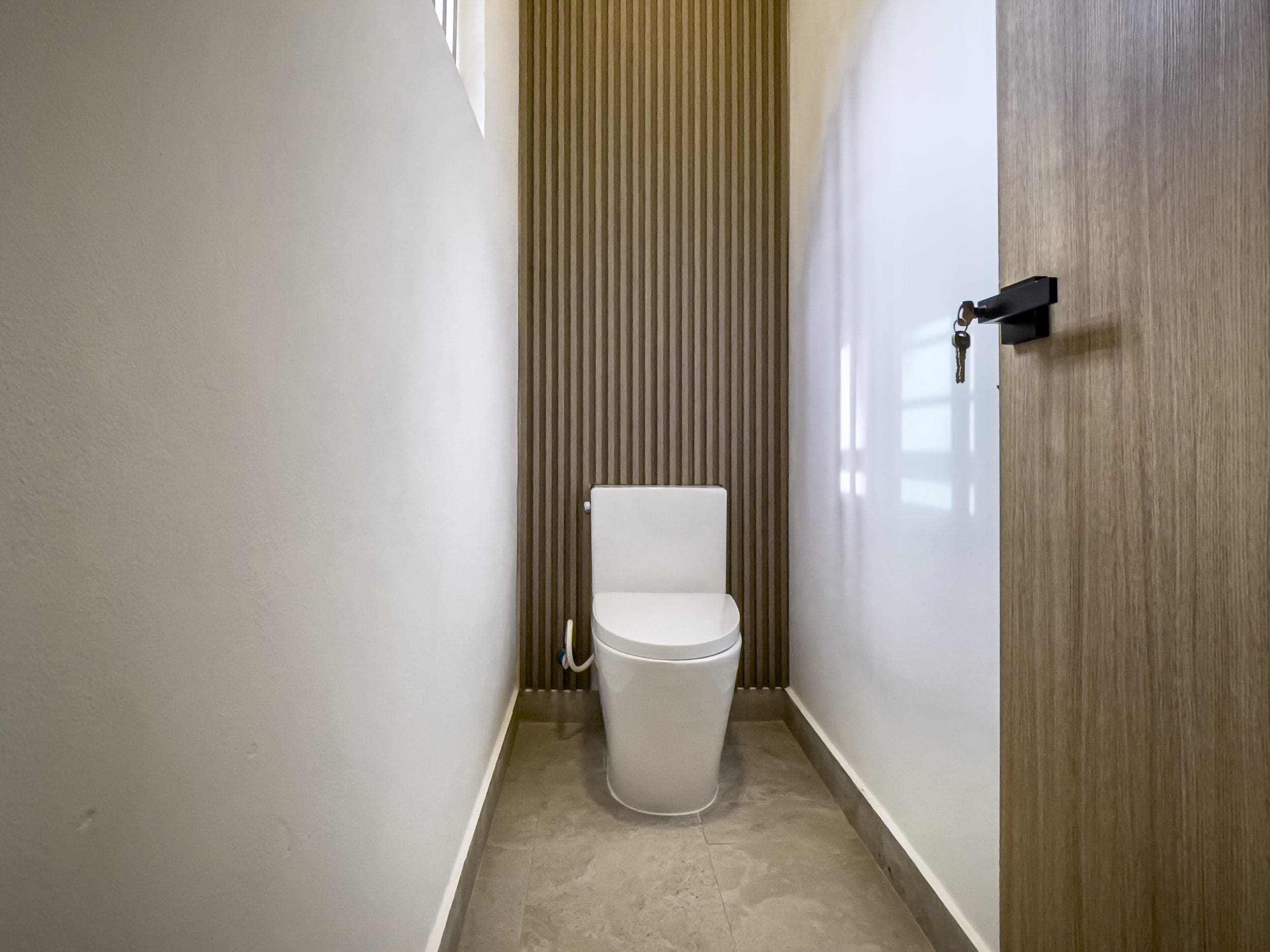 buyDRproperty Modern bathroom with white toilet and wooden accent wall. Villa For Sale. Sosua Real Estate
