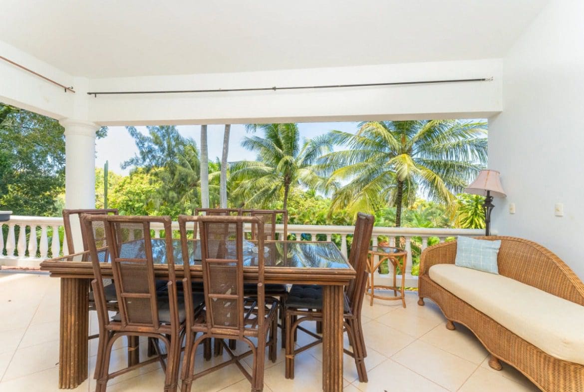 buyDRproperty Tropical patio with dining table, chairs, and chaise lounge overlooking palm trees. Sosua Real Estate
