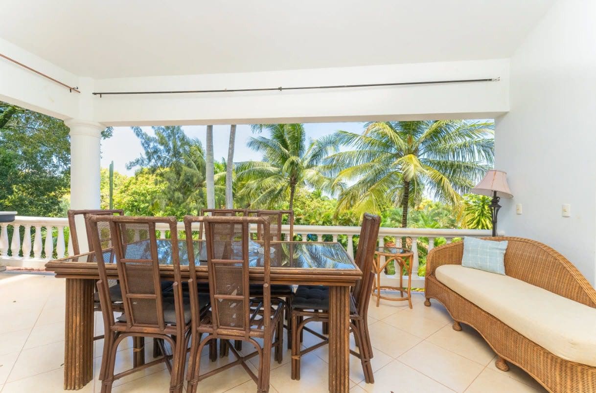 buyDRproperty Tropical patio with dining table, chairs, and chaise lounge overlooking palm trees. Sosua Real Estate