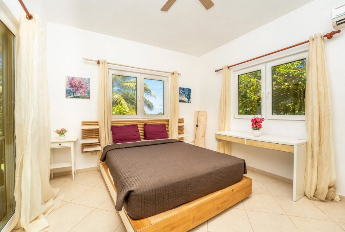 buyDRproperty Tropical bedroom in a villa for sale. Features a bed, windows, and desk. Sosua Real Estate