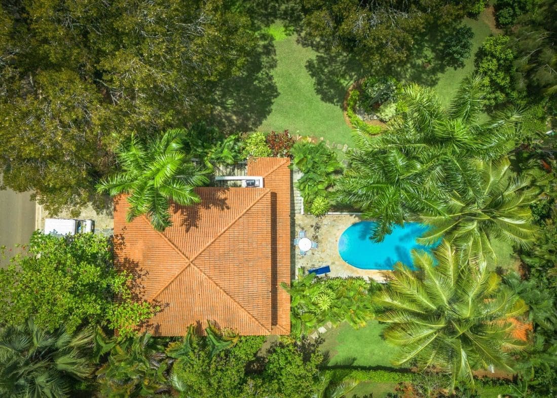 buyDRproperty Aerial view of a tropical villa with a pool surrounded by lush greenery. Sosua Real Estate