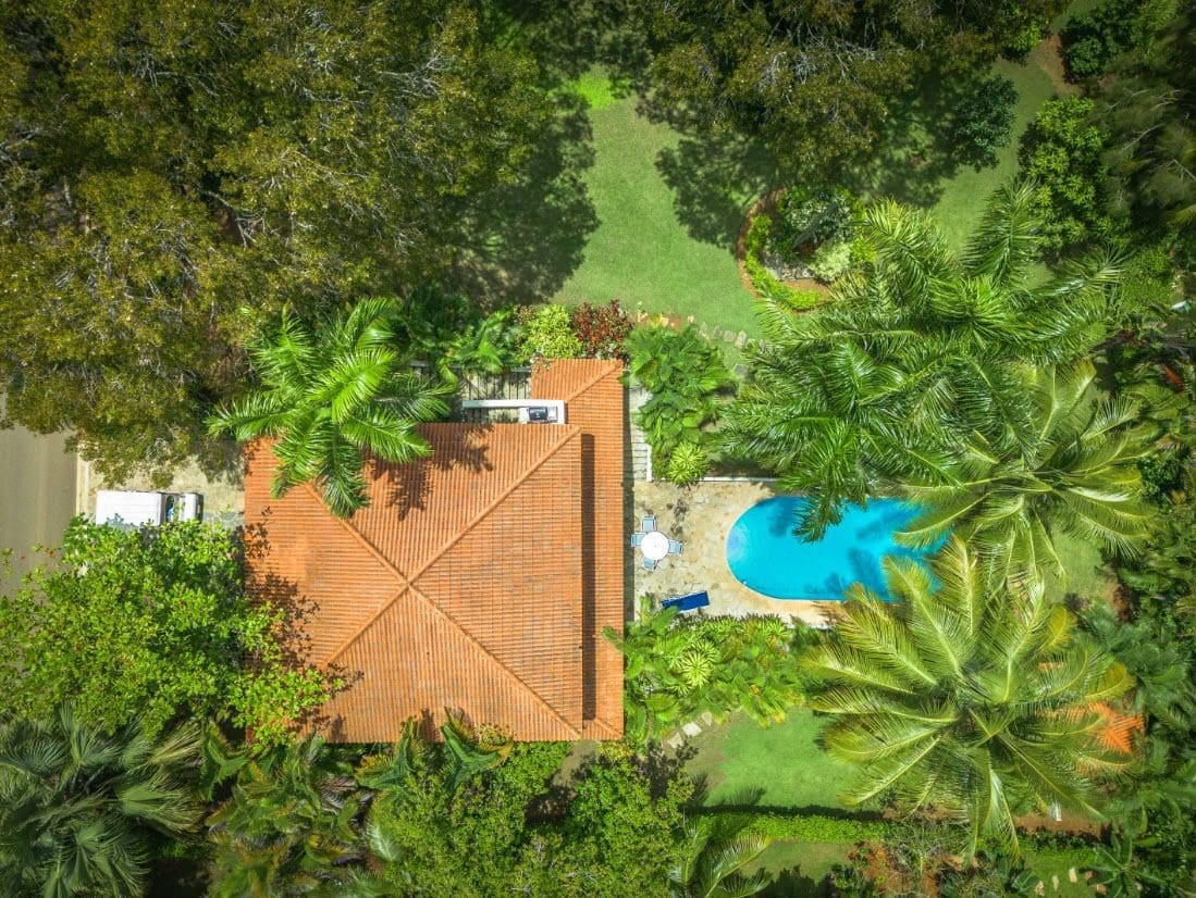 buyDRproperty Aerial view of a tropical villa with a pool surrounded by lush greenery. Sosua Real Estate