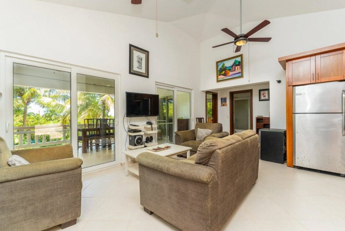 buyDRproperty Tropical villa living room with sofa, sliding doors, and a view of palm trees. Sosua Real Estate