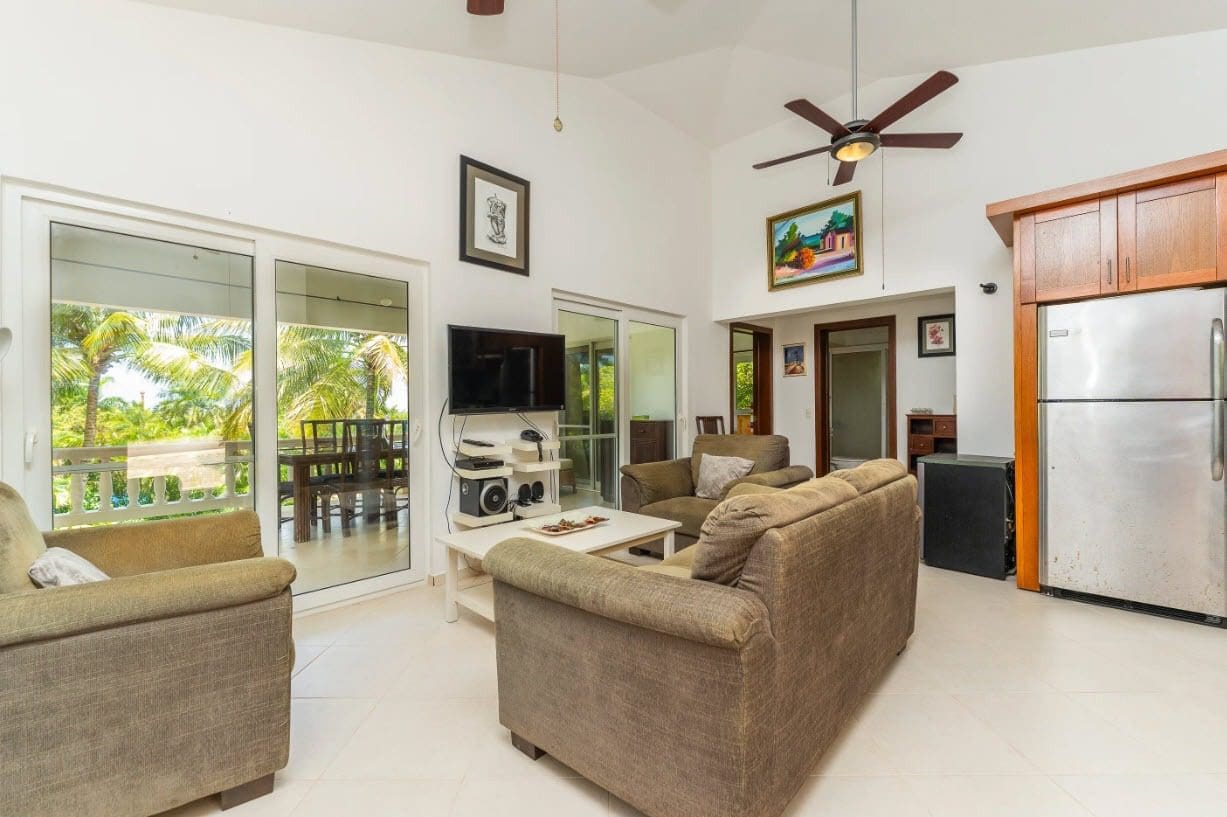 buyDRproperty Tropical villa living room with sofa, sliding doors, and a view of palm trees. Sosua Real Estate