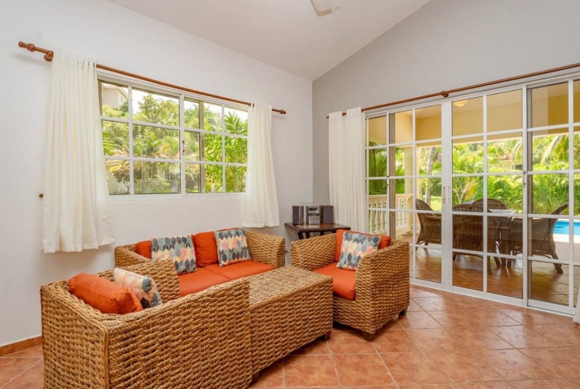 buyDRproperty Living room with wicker furniture, orange cushions, and view of the garden. Sosua Real Estate