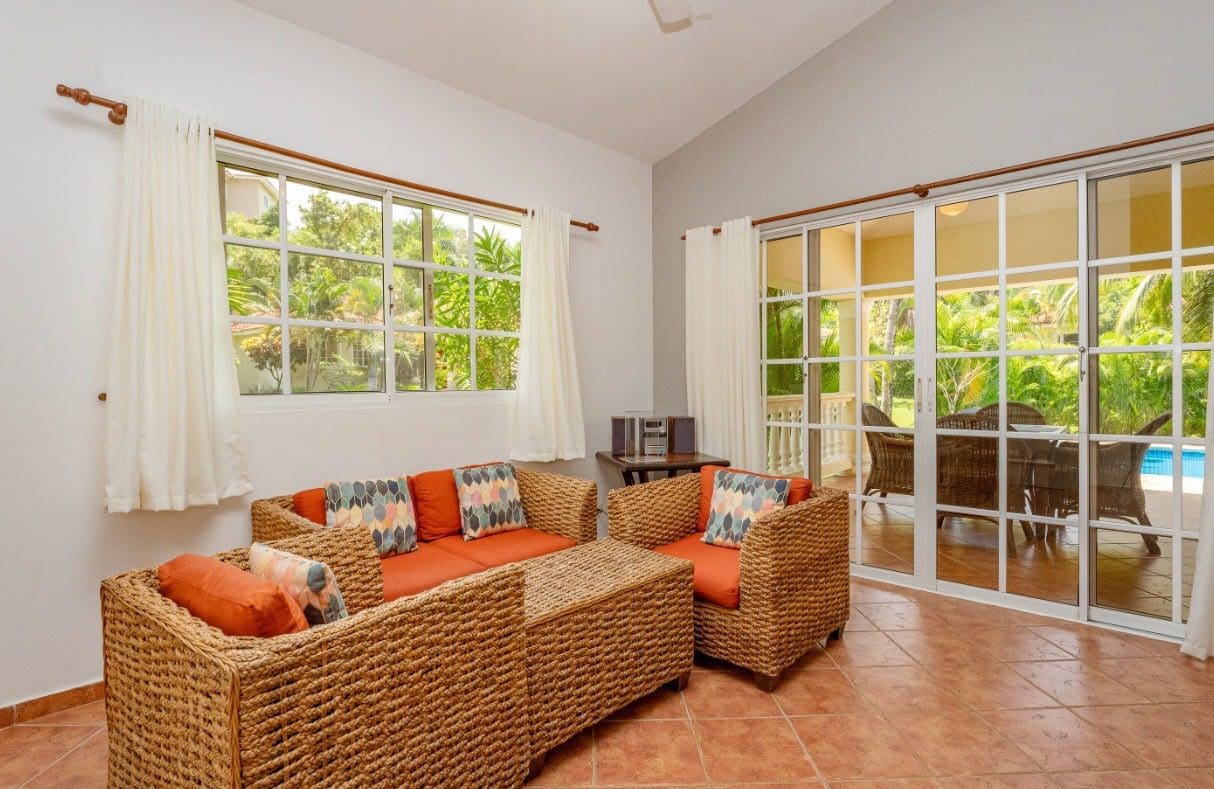 buyDRproperty Living room with wicker furniture, orange cushions, and view of the garden. Sosua Real Estate