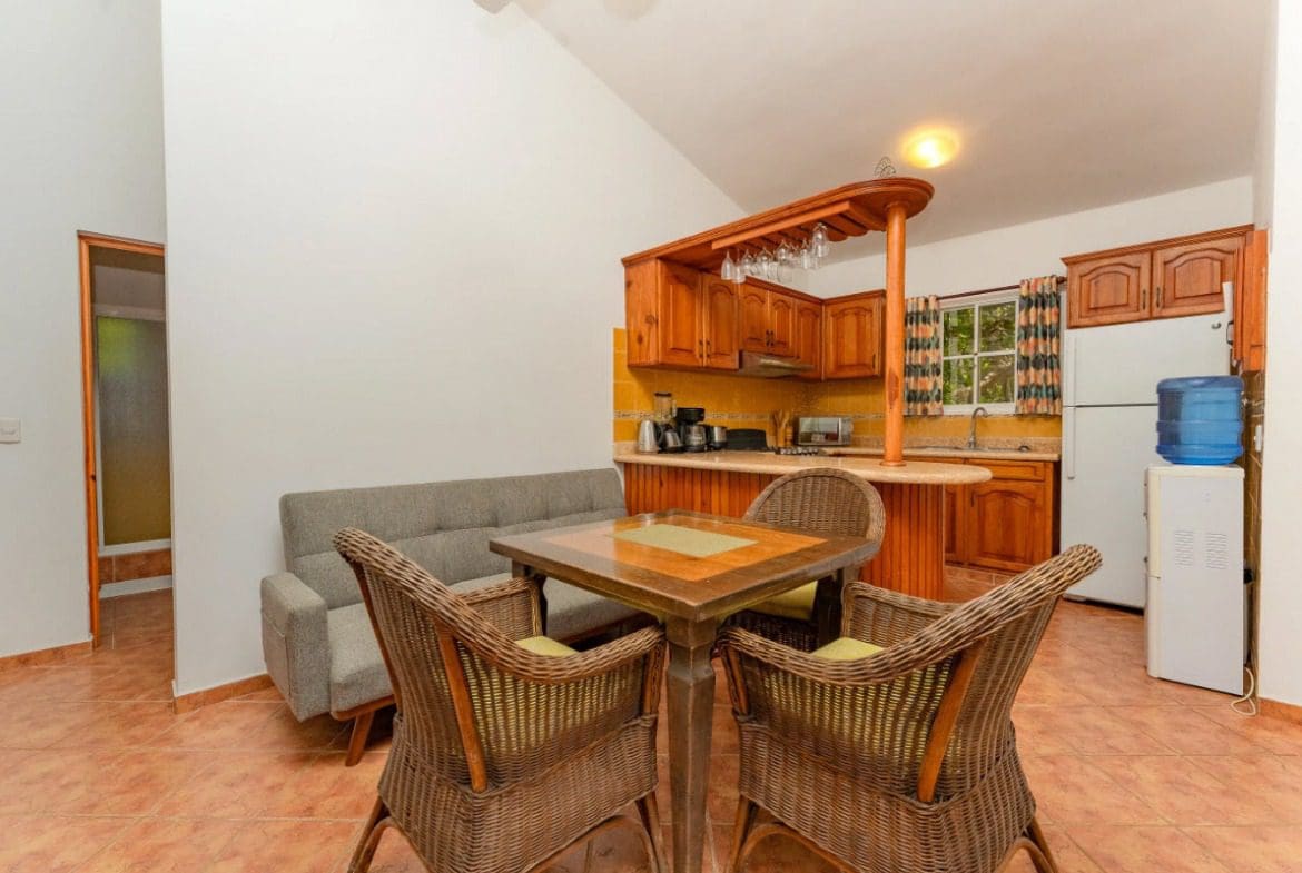 buyDRproperty Cozy kitchen and dining area in a villa, with wooden cabinets and wicker chairs. Sosua Real Estate